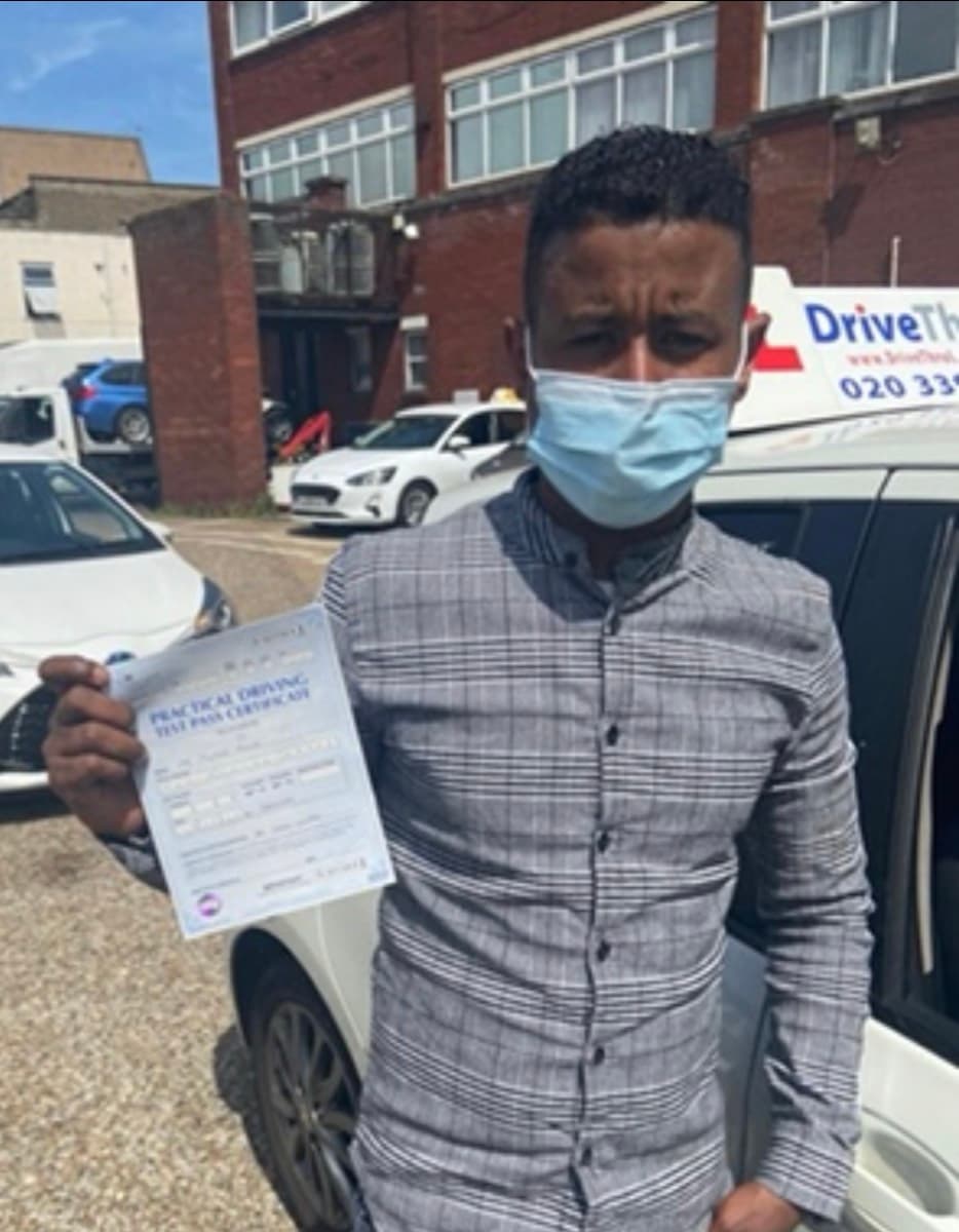 Student holding pass certificate next to DriveThruL car